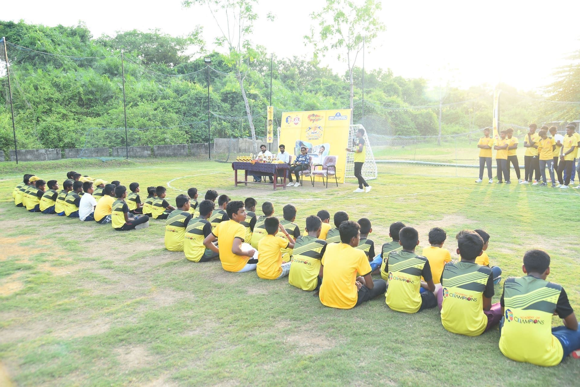 Academy of Champions juniors seated in front of a trophy table
